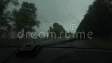 在恶劣的雨天驾驶，在汽车行<strong>驶过</strong>程中通过挡风玻璃观看乡村道路。 窗外的雨滴
